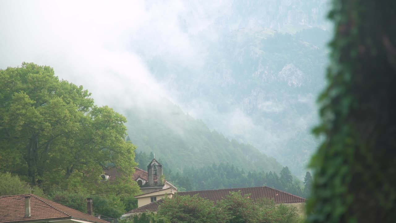 Foggy morning in Konitsa a traditional village in Epirus region in Greece, day shot of the forest and village houses view and ivy plant on front