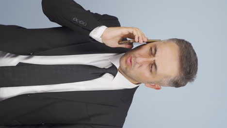 vertical video of businessman getting interrupted and angry while talking on the phone.