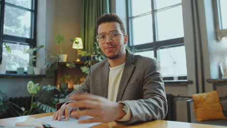young man talking at camera during online business meeting or class