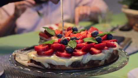 close up of a strawberry tart cutting, people eating around