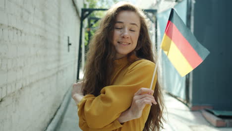 young woman holding german flag in a city alley
