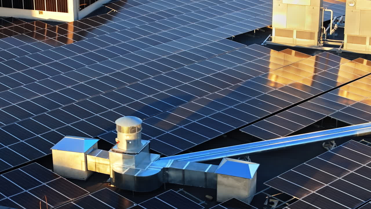 Aerial drone view of solar panels at sunset. Photovoltaics on top of the roof of the building. Alternative electricity source. Concept of sustainable resources