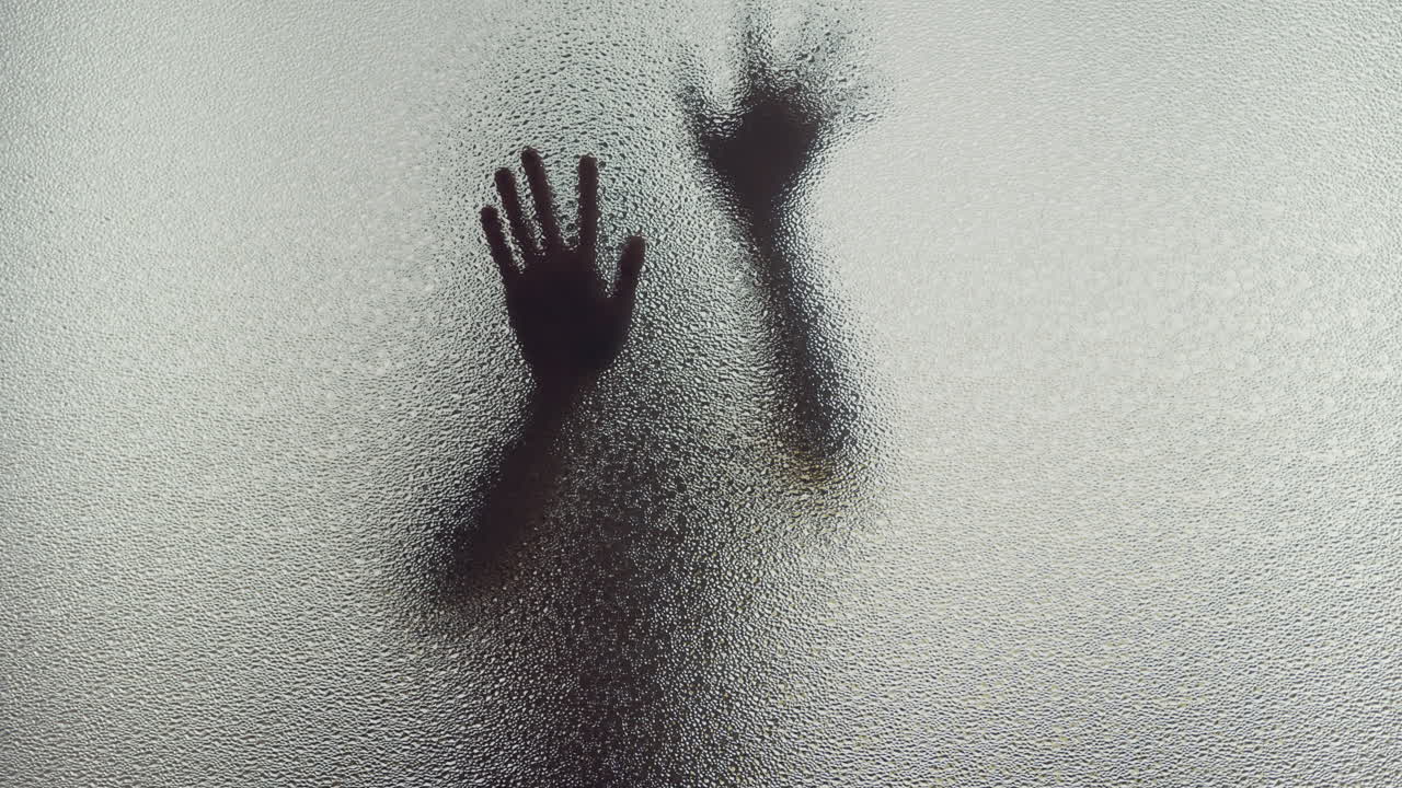 A female silhouette behind the frosted window slowly touches the glass