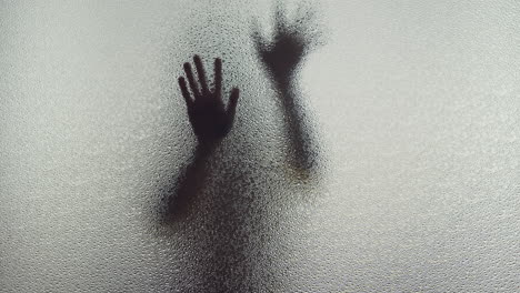 A female silhouette behind the frosted window slowly touches the glass
