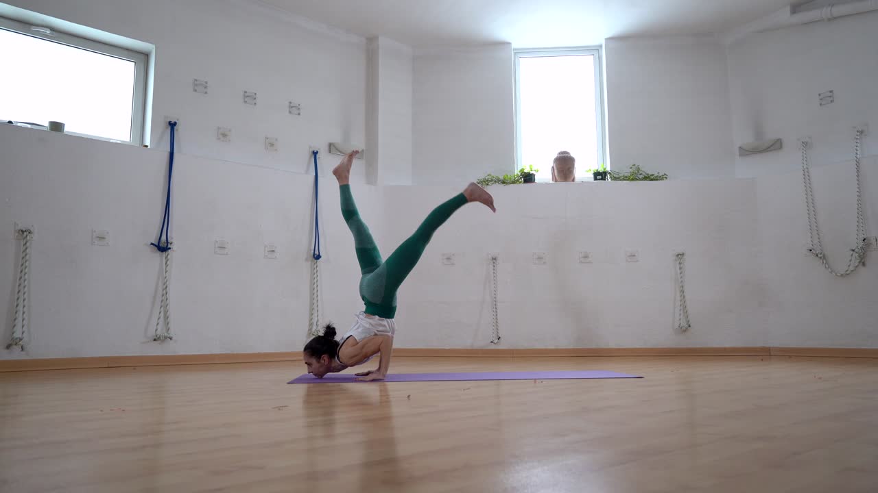 mujer flexible realizando postura de pie de barbilla en el tapete de yoga