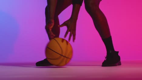 close up studio portrait of male basketball player dribbling and bouncing ball against pink lit background 8