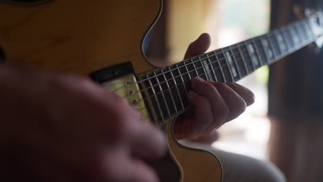 close up view of a man's hand playing an electric guitar in a home studio.