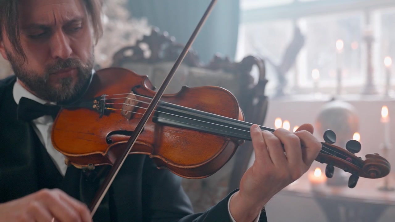 Uomo che suona il violino con l'archetto in una elegante stanza a lume di candela