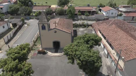 vista aérea de una pequeña iglesia en el interior de la pequeña ciudad con bueyes de pasto y vacas en el fondo