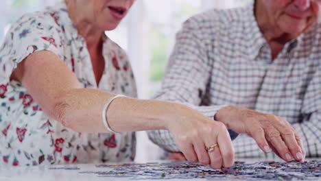 Senior-couple-doing-jigsaw-puzzle-at-home,-mid-section