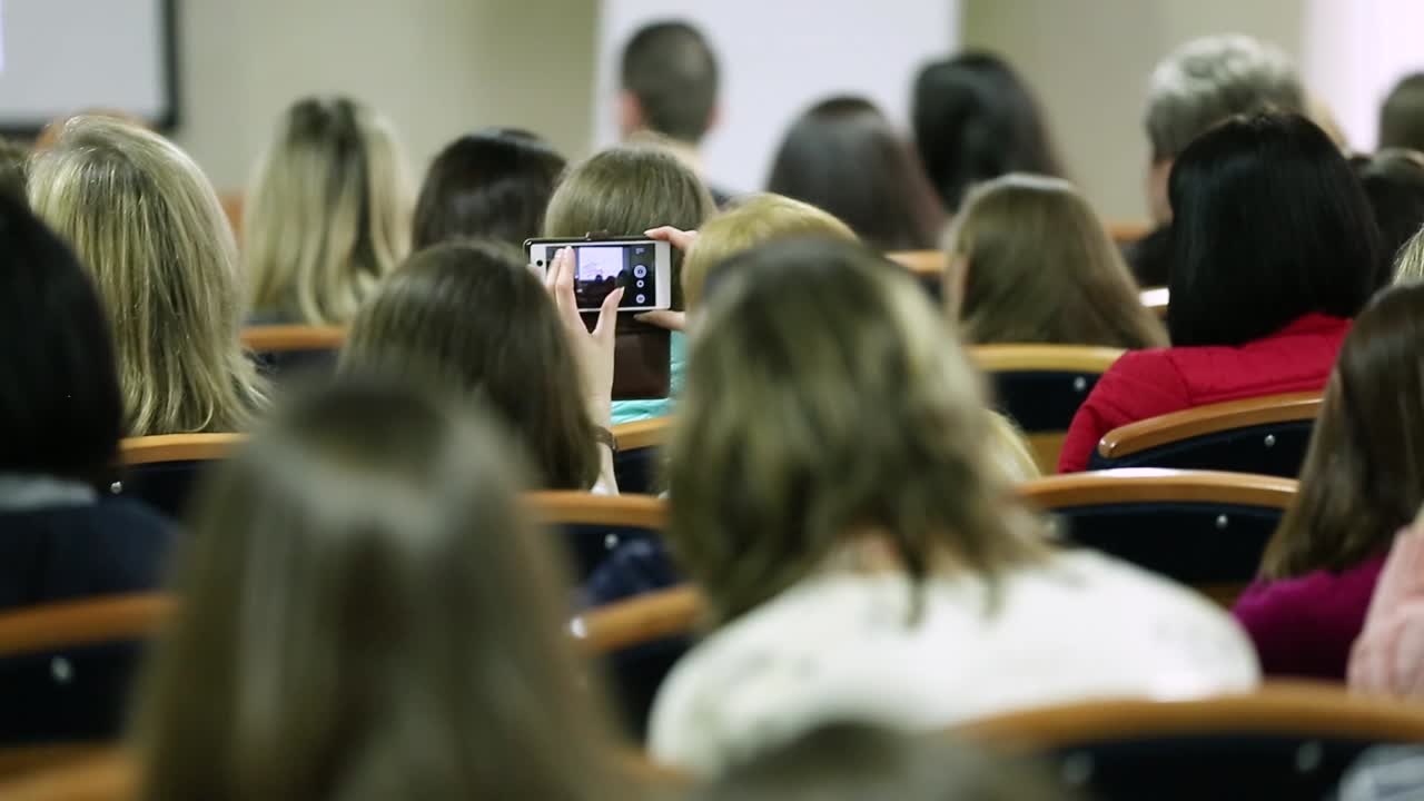 Audience Listening To Presentation At Conference. Businessman speaking at a podium in a conference or seminar