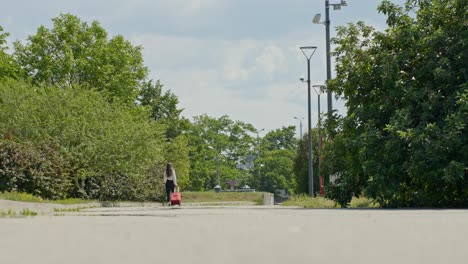 mujer elegante caminando en cámara lenta tirando de una maleta roja, escena urbana