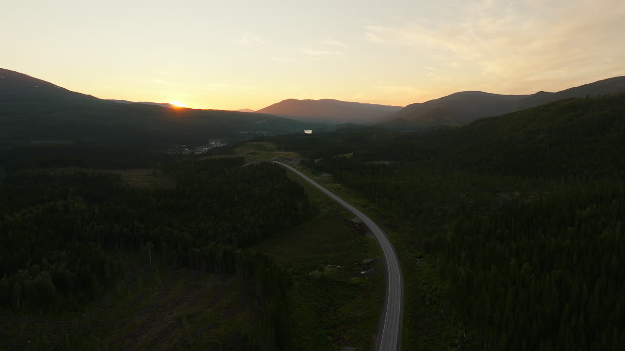 sol de medianoche sobre la ruta europea a través del bosque boreal en el norte de noruega