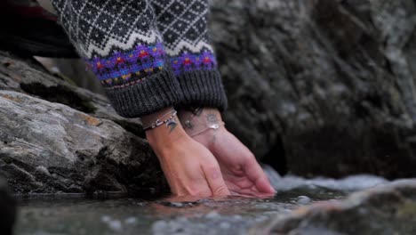 hands scooping water from the river in norway