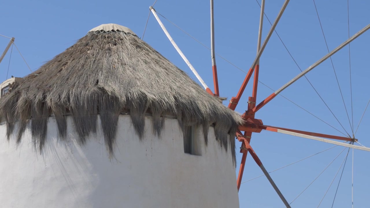 Primo piano di un pittoresco mulino a vento bianco con tetto di paglia, un punto di riferimento emblematico di Mykonos, Grecia. Inquadratura con movimento verticale verso l'alto.
