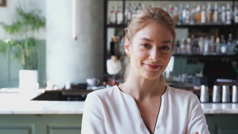 portrait of confident female owner of restaurant bar standing inside by counter