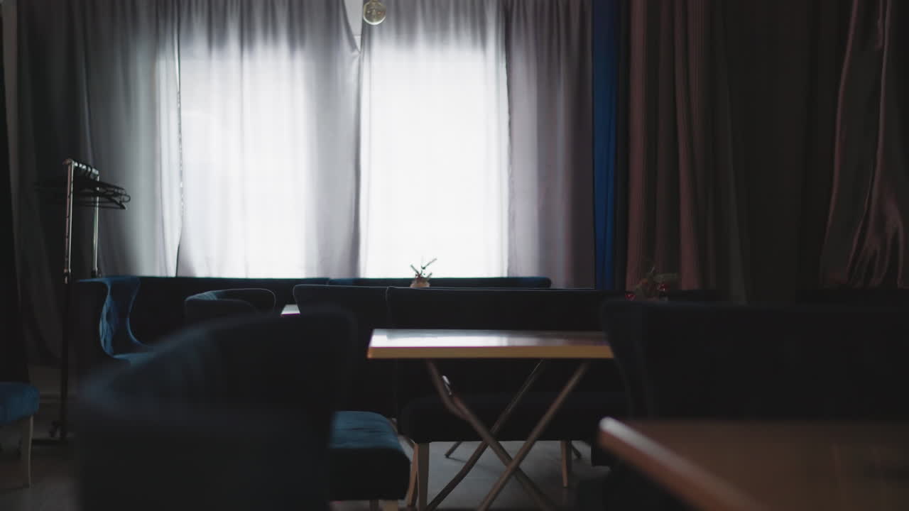 Interior of cozy caf with velvet blue seating and wooden tables. Large window with soft natural light filtering through curtains. Calm and peaceful atmosphere enhanced by minimalist d cor
