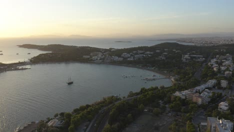 Una-Vista-Aérea-De-Una-Pequeña-Cuenca-Con-Un-Velero-Durante-La-Puesta-De-Sol-Junto-Al-Mar-En-Grecia