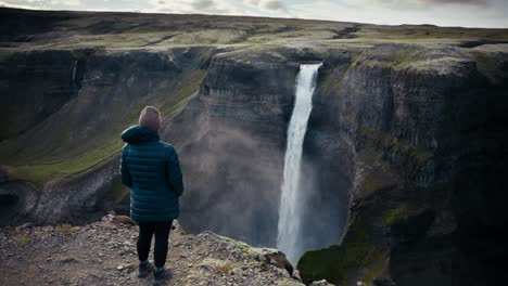 Attraktives-Mädchen-Blickt-über-Den-Canyon,-Einen-Unglaublich-Epischen-Und-Hohen-Wasserfall