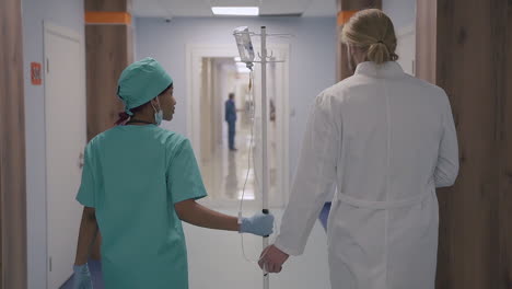 a cute young american nurse and a young doctor with long, blond hair walk together down the hospital corridor