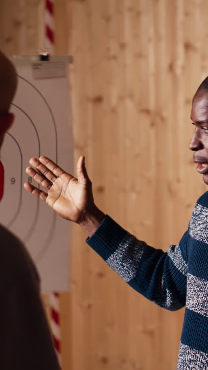 Vertical video Shooting gallery instructor explaining bullseye scoring system to customers