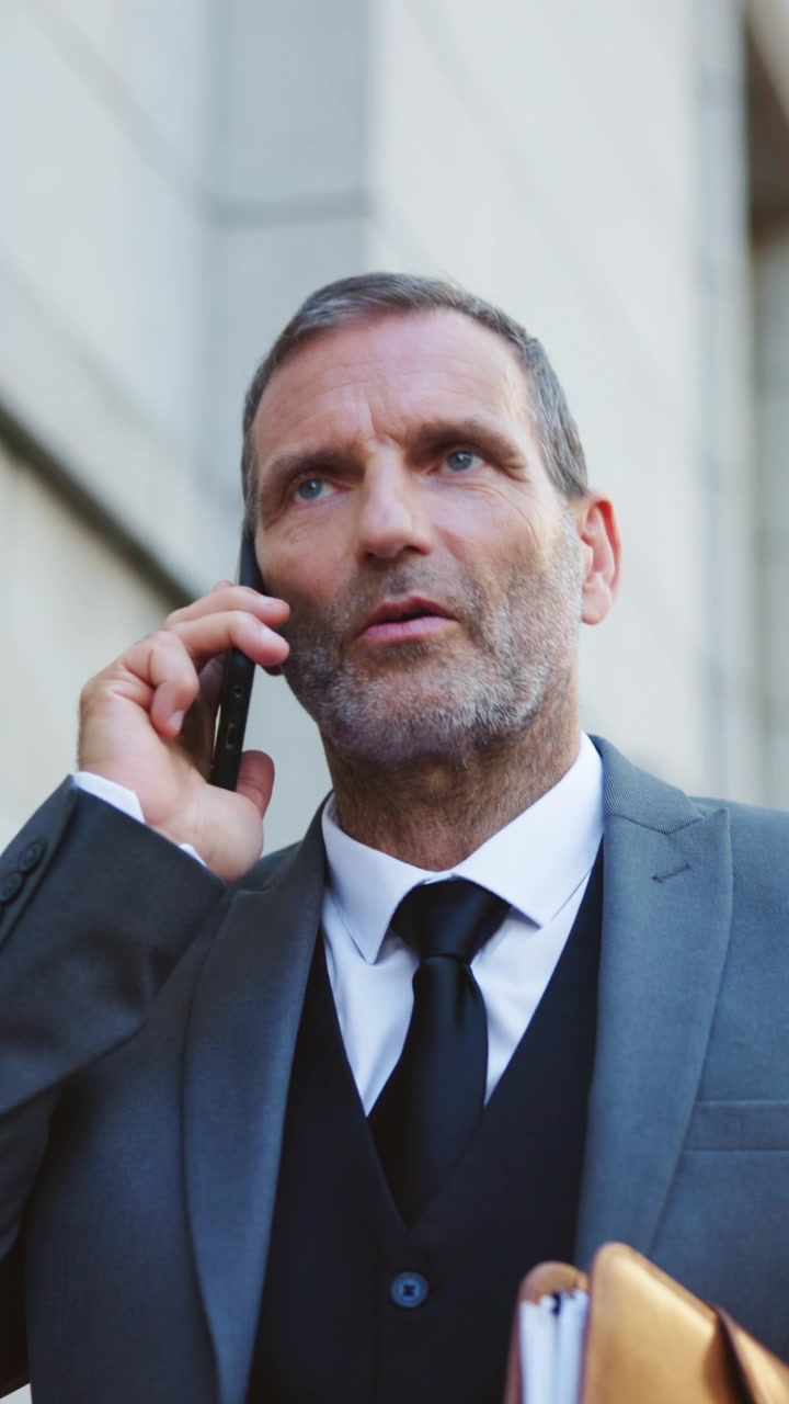 Uomo d'affari maturo che parla al cellulare mentre cammina all'aperto