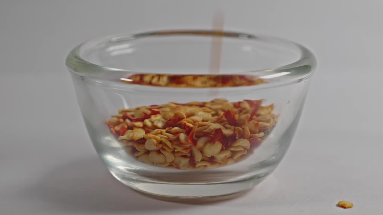 Chilli Flakes falling in small glass bowl, 4k, stable shot