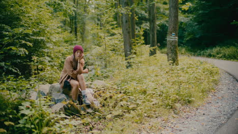 woman taking rest sitting on rock by plants in forest