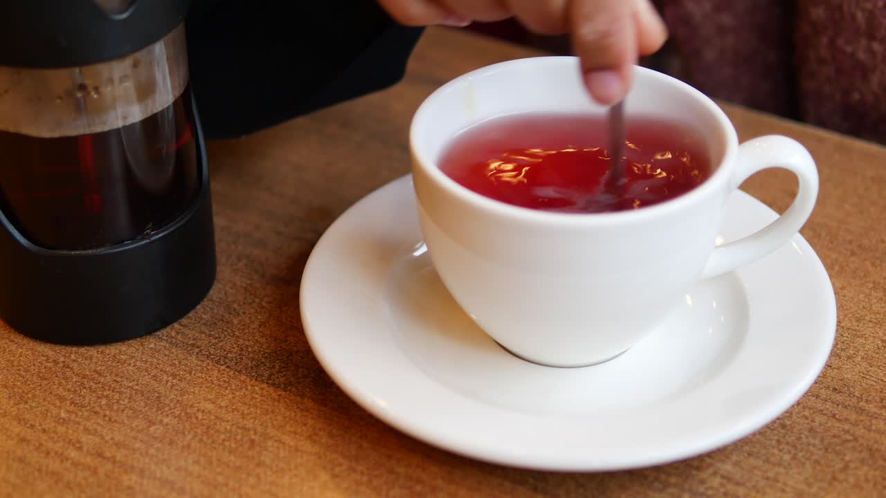 Person stirring tea in a cup