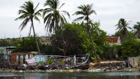 tilt-up reveal shot of dilapidated house and garbage area on river bank of son hai