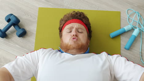 funny overweight man eating bread while lying on an exercise mat