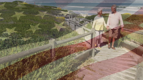 animation of happy senior caucasian couple holding hands on beach, flag of united states of america