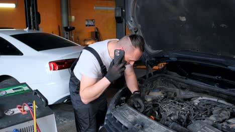 a mechanic talking on the phone while working on a car engine in a garage