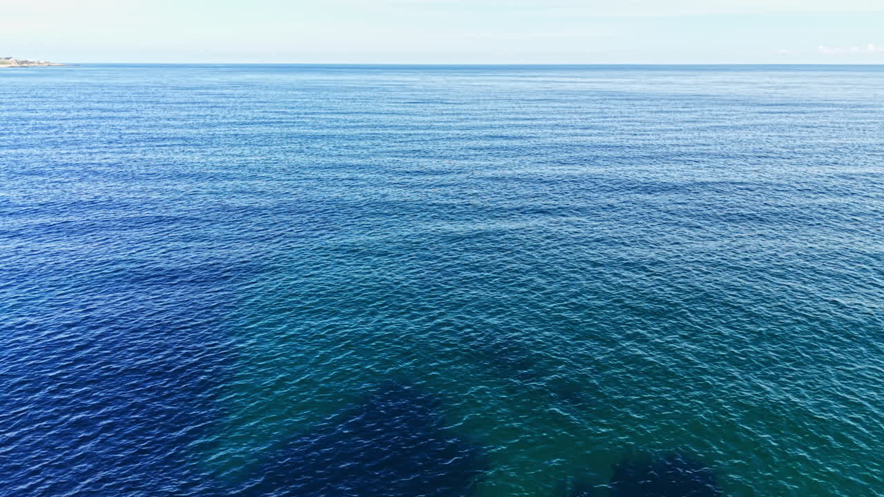 明るい空の下、広大な青い海がどこまでも広がり、昼には探検と静けさを誘います。