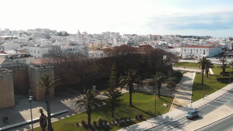 Medieval-fortified-city-walls,-palm-trees-and-cityscape,-Lagos,-Algarve,-Portugal