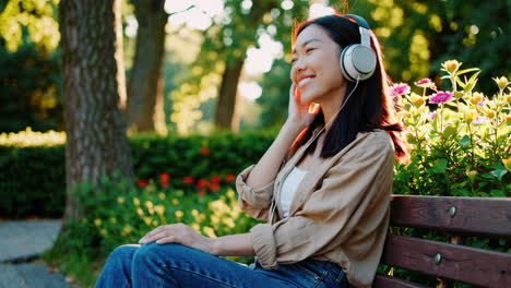 happy woman listening to music on headphones in a park