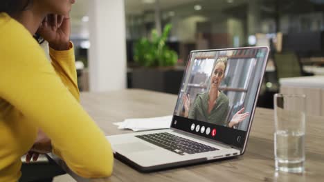 Mujer-Birracial-Usando-Una-Computadora-Portátil-Para-Videollamada,-Con-Un-Colega-De-Negocios-En-La-Pantalla