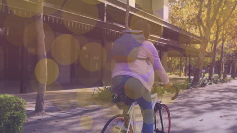 yellow spots of light floating against woman riding a bicycle on the street