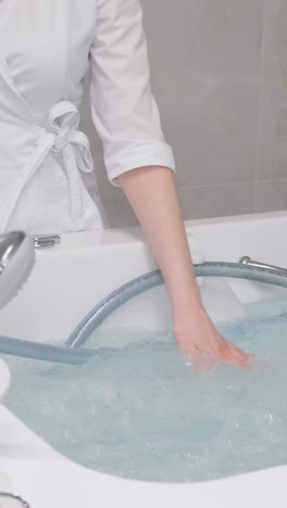 a female doctor fills a hot tub with water in a luxury spa. relaxing procedures in the beauty center. vertical video