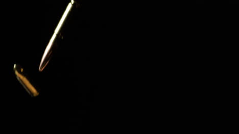 300 aac blackout and 9mm luger bullets dropping in slow motion against black background