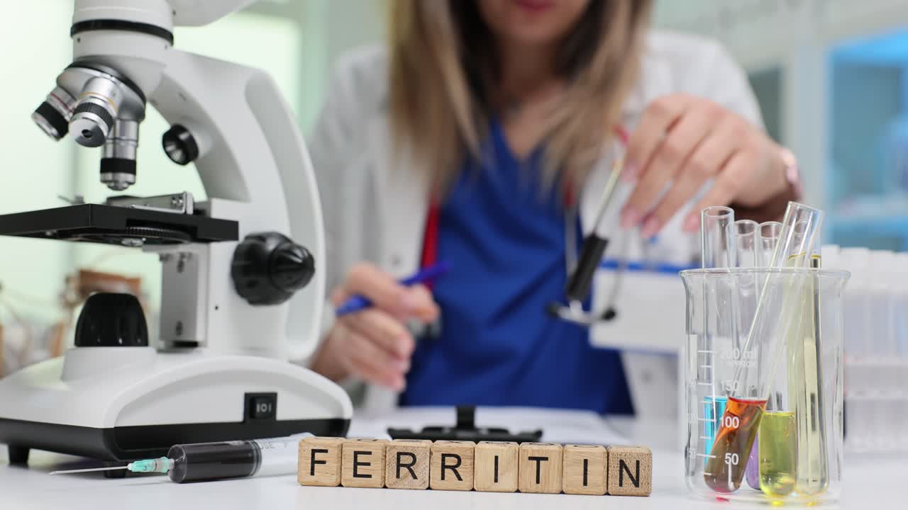 Mattoncini di legno compongono la parola ferritina mentre lo specialista di laboratorio analizza il sangue.