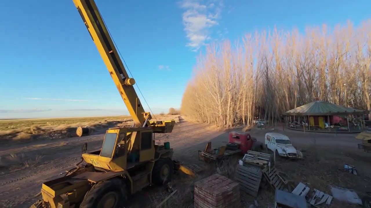 Guindaste Móvel e Pátio de Máquinas Antigas no Campo, Vista Aérea de Drone FPV de Voo Rápido da Paisagem.