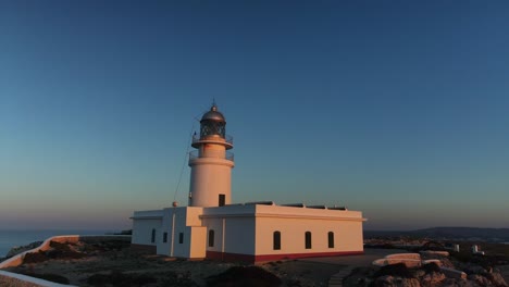 El-Resplandor-Dorado-Del-Faro-De-Cavalleria-En-España-Muestra-La-Escala-De-Los-Enormes-Acantilados-A-Lo-Largo-De-La-Costa