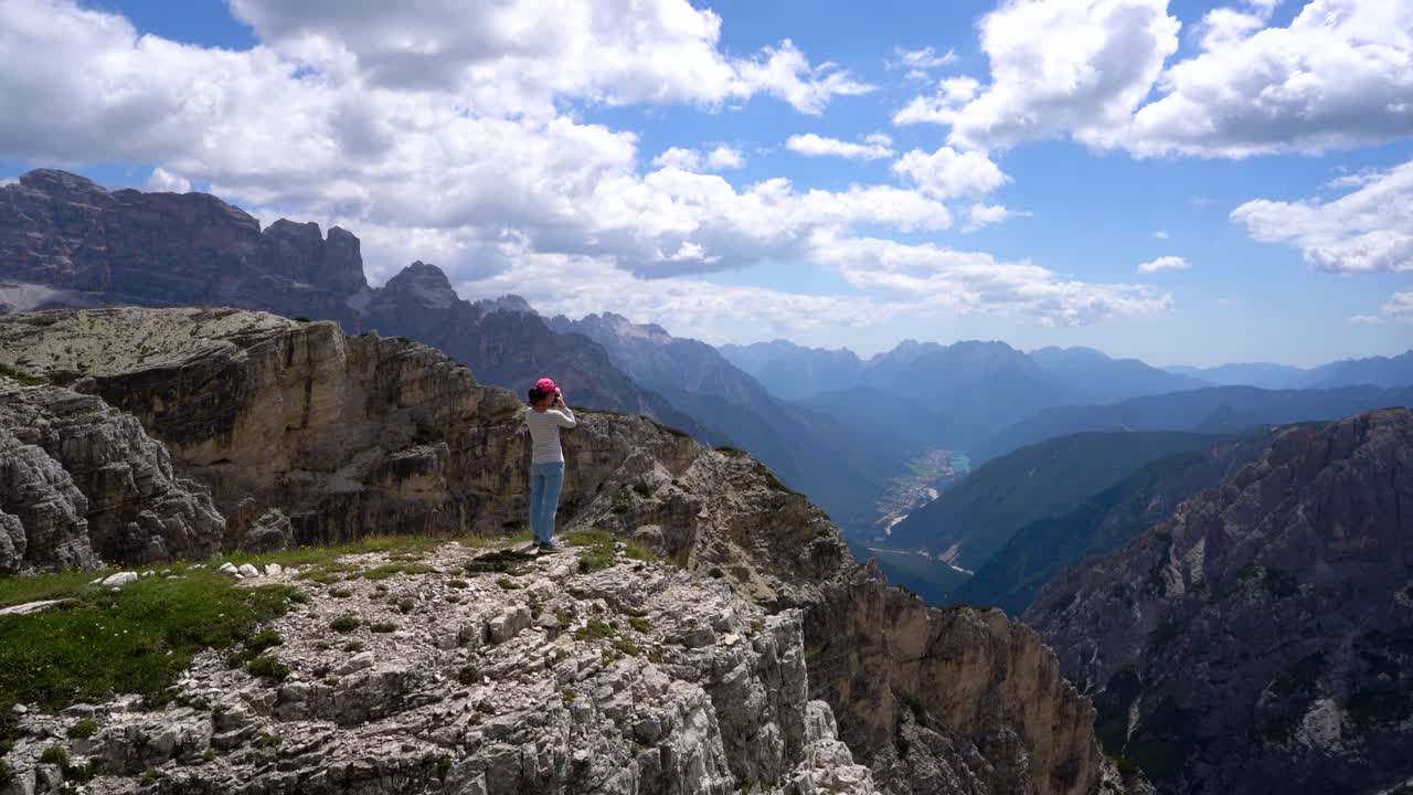 una mujer excursionista de pie alcanzando los máximos alpes dolomitas.