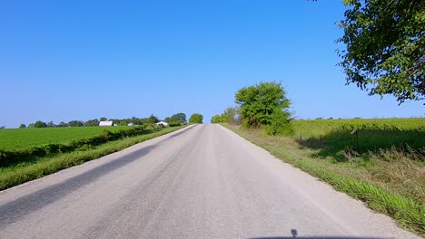 pov while driving thru rural iowa on a paved country road on a bright sunny summer afternoon in rural western illinois