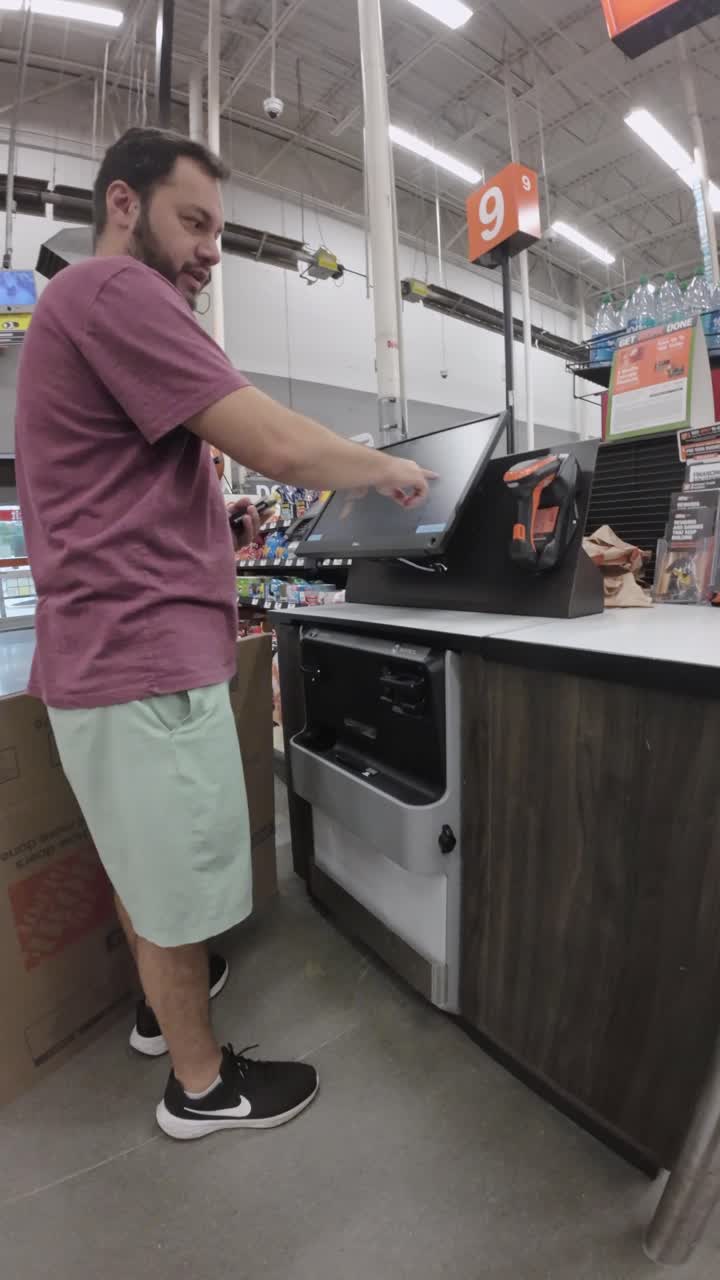 Uomo che scansiona una scatola di cartone al self-checkout in un negozio al dettaglio