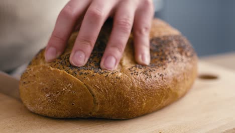 close up of hands of woman cutting fresh bread  at the kitchen.