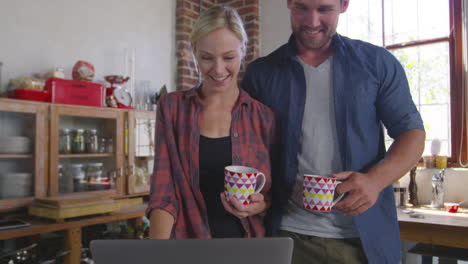 una joven pareja blanca usa una computadora portátil en la cocina, ángulo bajo de primer plano, filmado en r3d