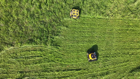 top down aerial view of two robotic lawn mowers in grassland on sunny summer day