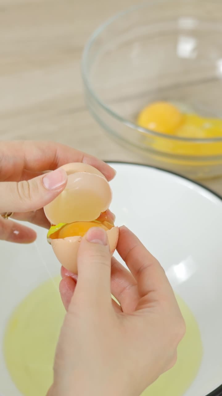Close-up of hands separating an egg yolk from the white for a tiramisu